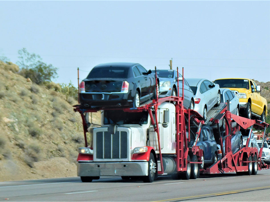 Big rig hauling car hauler trailer with vehicles.