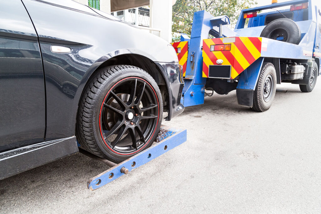 Tow truck towing a broken down car on the street.