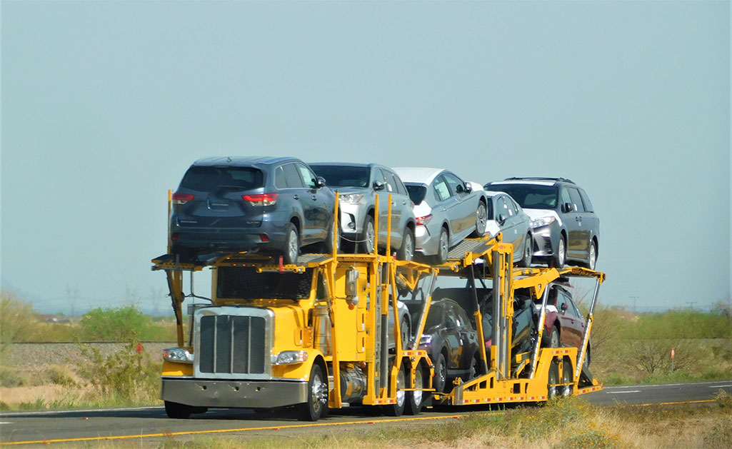 Yellow car hauler hauling a big rig.