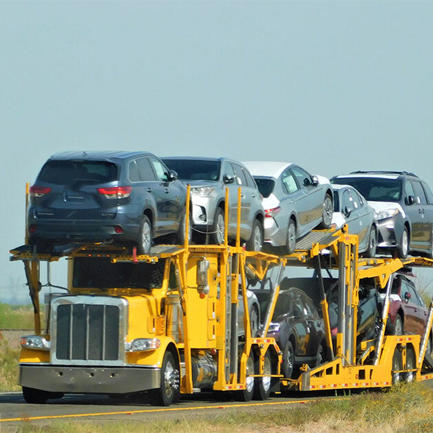 Yellow car hauler hauling a big rig.